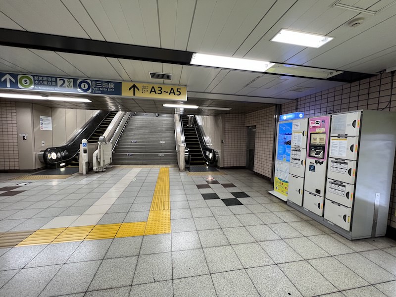 コインロッカー横の階段・エスカレーターを上がると都営三田線・新宿線本八幡方面の改札。