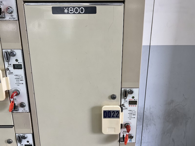 硬貨投入口近くの表示は「700円」なのに、コインロッカーに貼り付けのステッカーは「800円」。