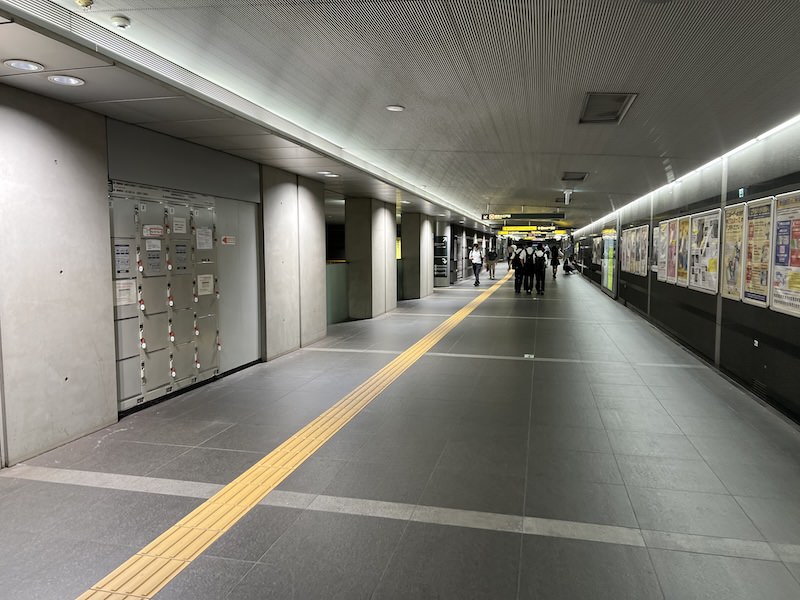 コインロッカーから大江戸線ホーム階へのエスカレーター、さらに奥にある浅草線のホーム階への階段・エスカレーターへの通路を見る。