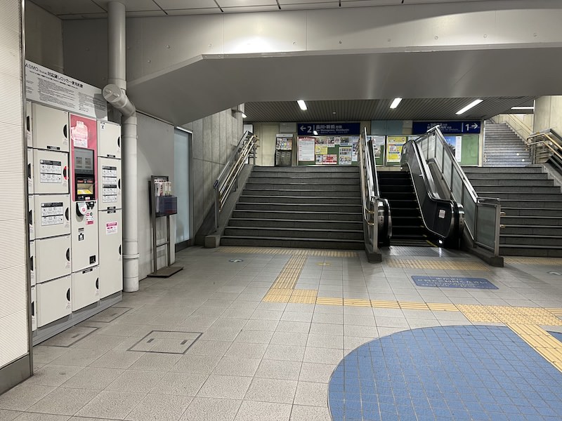 コインロッカー側からホームへの階段・エスカレーターを見る。エスカレーターは上りのみ、エレベーターはこの写真の手前側。